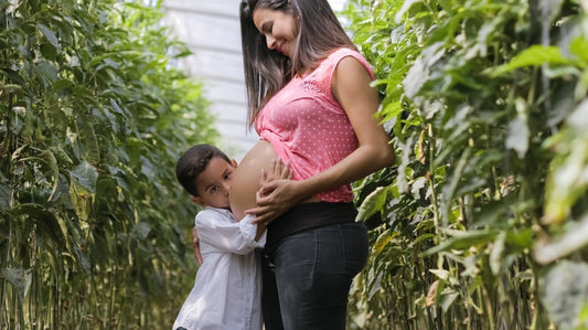 An expectant mum admiring her bump with her other child