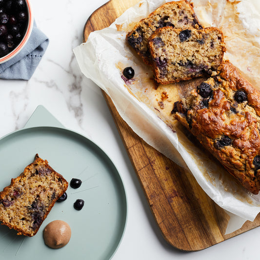 Banana and Blueberry baked loaf on a chopping board with fresh blueberries