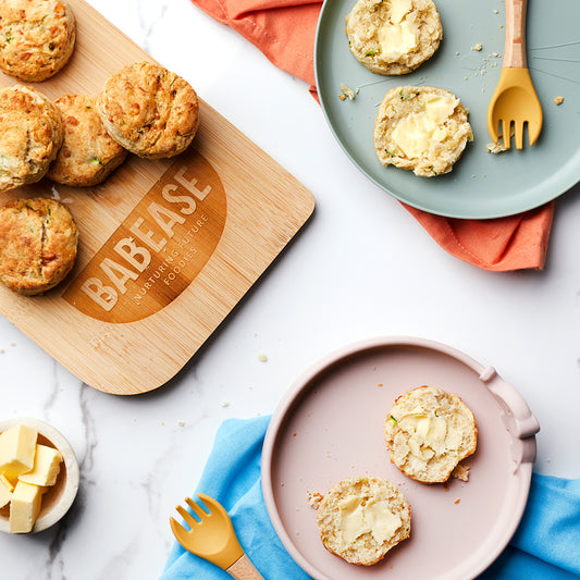 Freshly baked Scones whole on a wooden chopping board and cut on weaning plates 