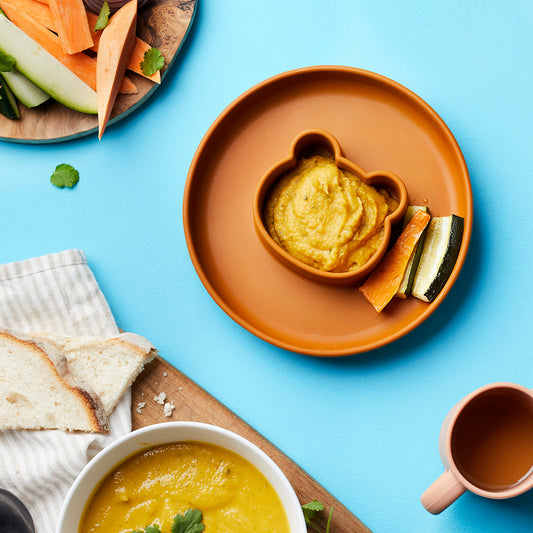 Orange spiced purée in a toddler safe bowl with roasted vegetable finger batons