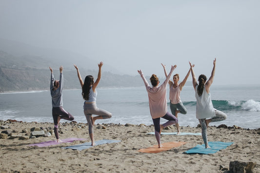 Mothers doing yoga exercises on a beach